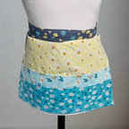 Colorful floral apron on a mannequin against a gray background