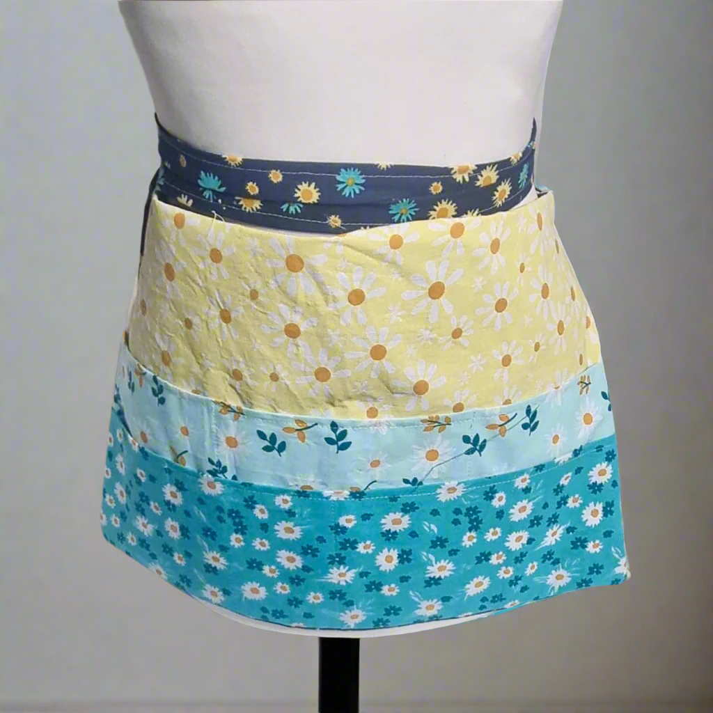 Colorful floral apron on a mannequin against a gray background