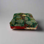 Decorative fabric pincushion with holly design on a plain background