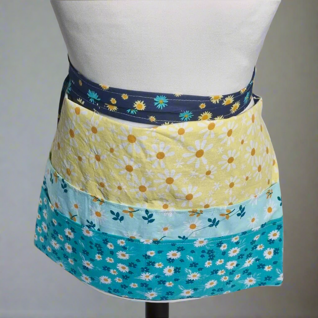 Floral-patterned apron on a mannequin against a gray background