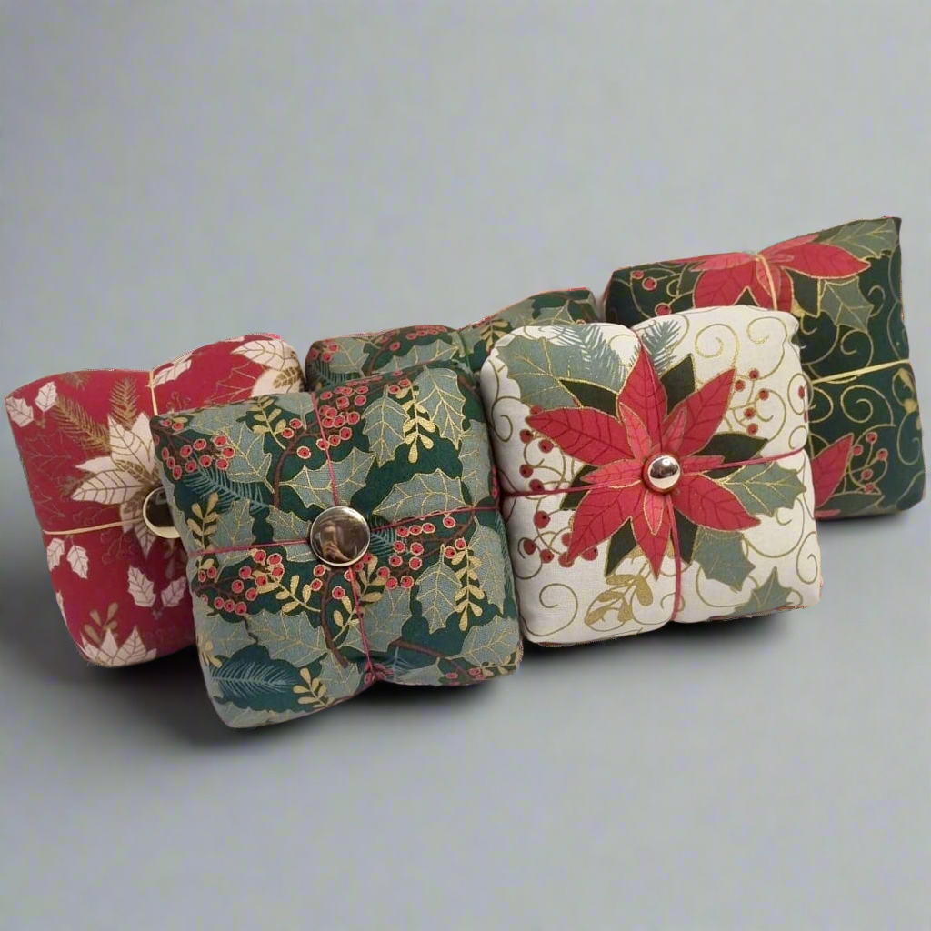 Five fabric pincushions with floral patterns on a light gray background