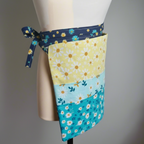 Floral patterned apron on a mannequin against a gray background