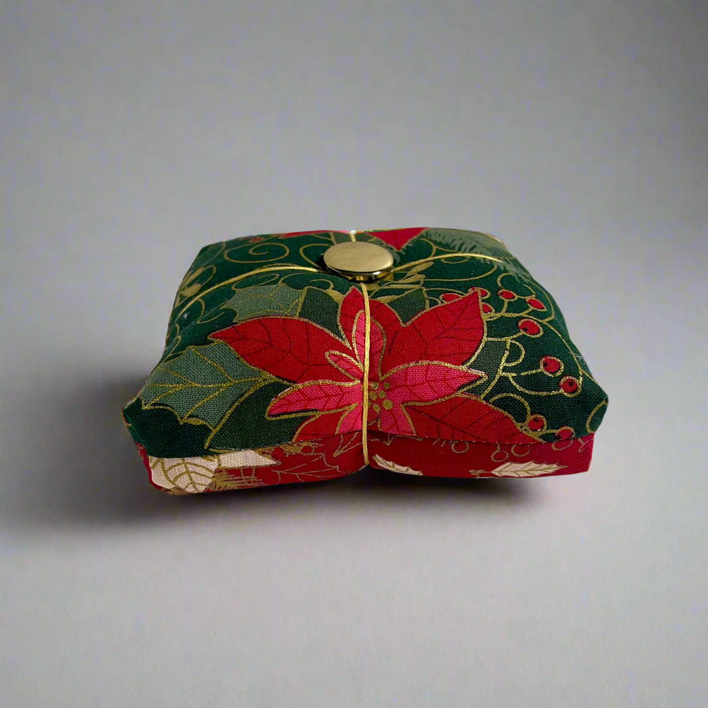 Decorative fabric pincushion with floral patterns on a plain background