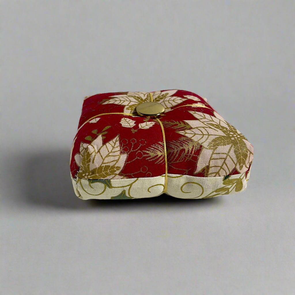Small square fabric pincushion with floral pattern on a gray background