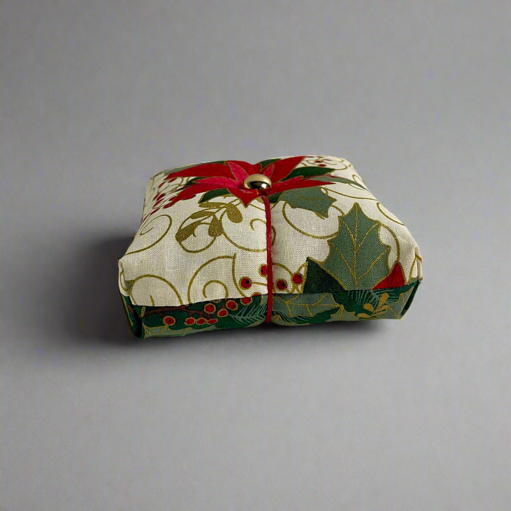 Small fabric pincushion with floral pattern on a gray background