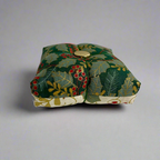 Small fabric pincushion with holly design on a light gray background