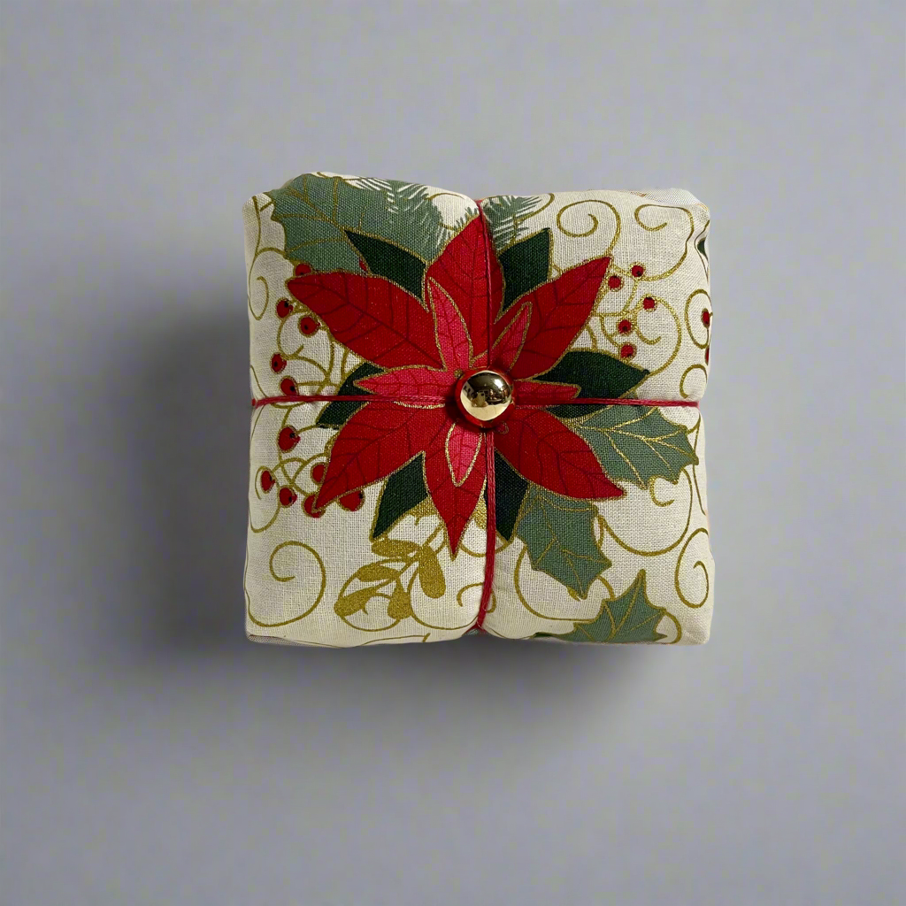 Decorative pincushion with red floral design on a light gray background
