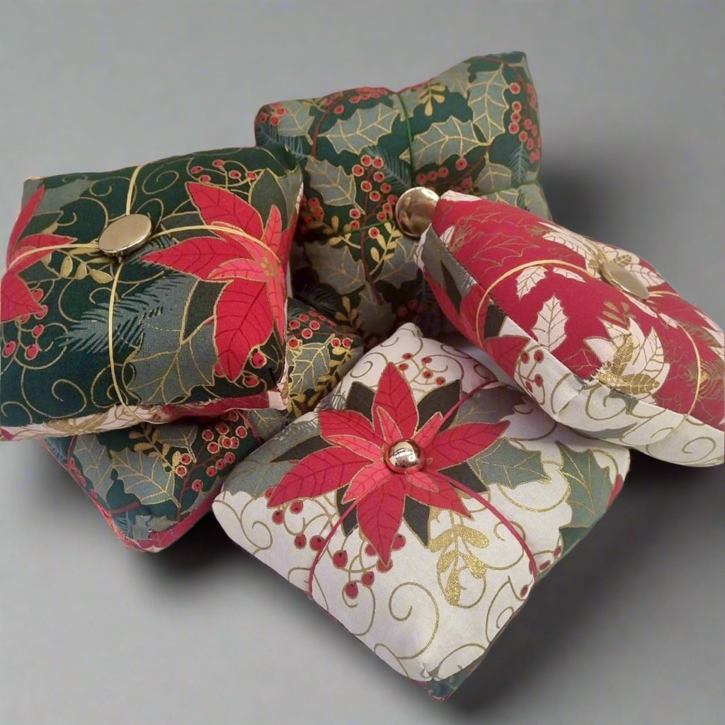 Decorative fabric pincushions with floral patterns on a gray background